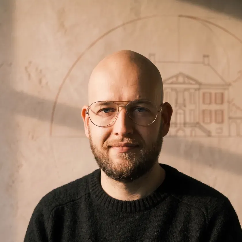 Portret van Matthijs Kruithof, grafisch ontwerper en webdeveloper van KruithofOntwerp in Slochteren, voor de Stucco Rosato kalkstuc-muur met de Fraeylemaborg-gravure en gouden passerboog